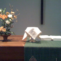 Lukas-kirkon alttaripöytä. Etualalla liinalla peitetty ehtoollismalja ja taempana avattu raamattu.