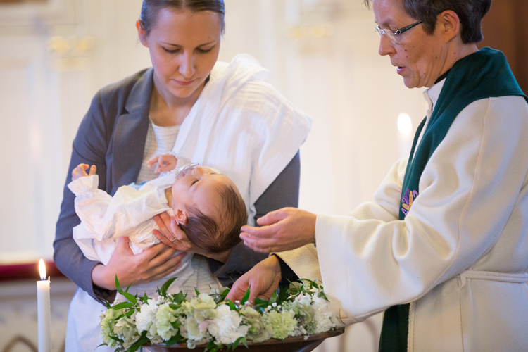 Eine Pfarrerin tauft ein Baby.